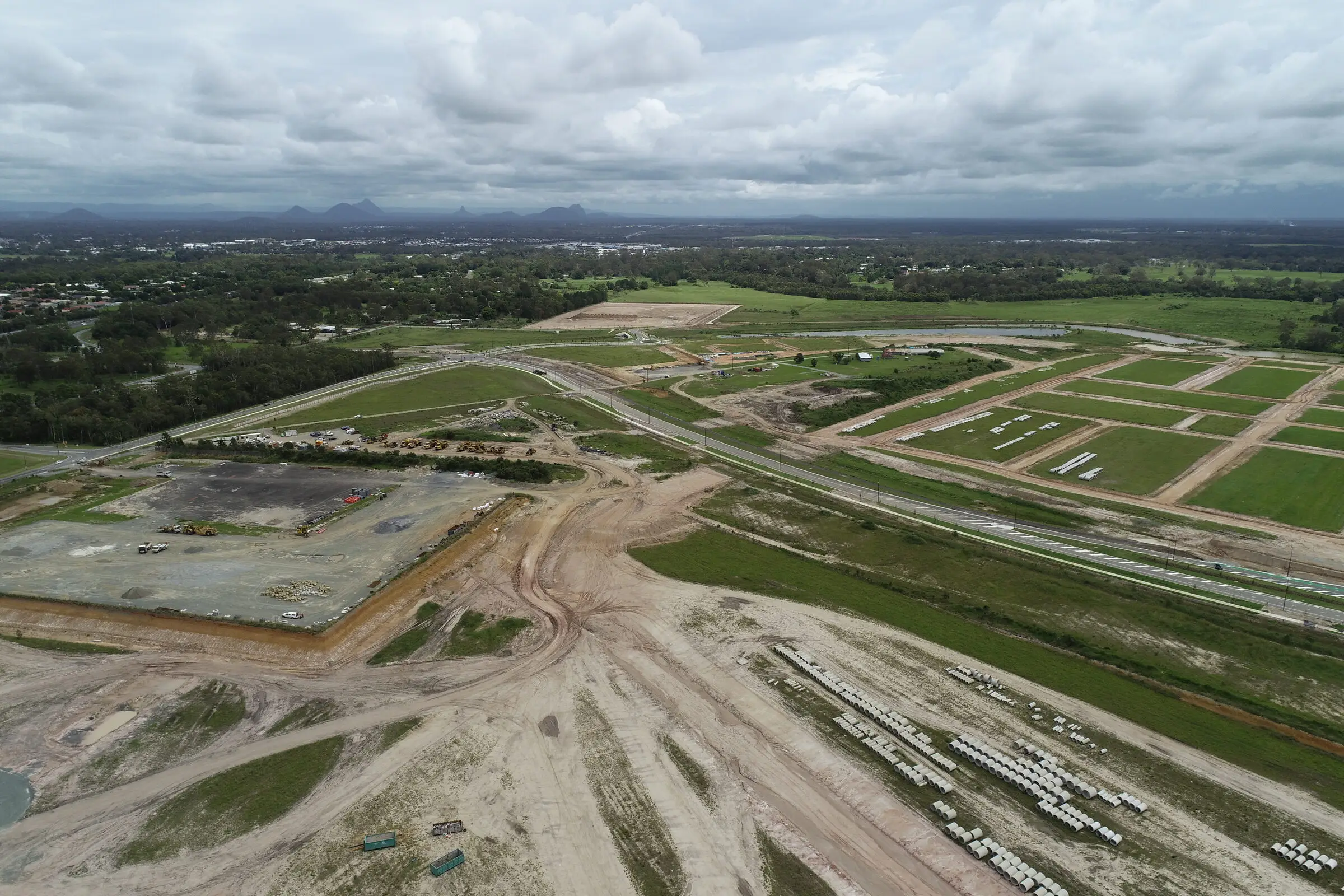 Aerial view of a greenfield land development with bulk earthworks, stockpiled drainage pipes and newly formed subdivision lots