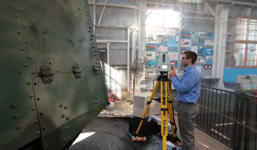 Surveyor operating a laser scanner beside the riveted hull of Mephisto