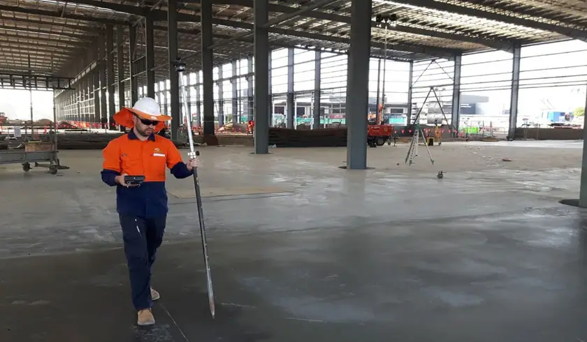 Surveyor setting out on the concrete slab inside the steel-framed MILVEHCOE building at Redbank