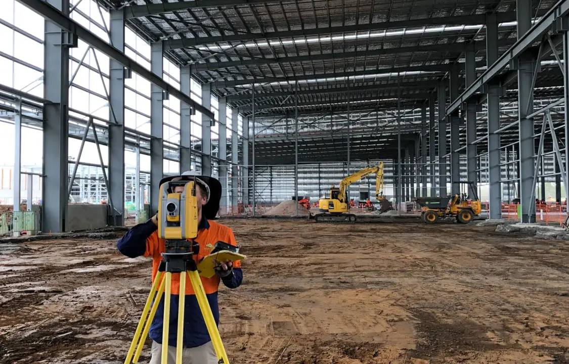 Surveyor with a total station inside the MILVEHCOE warehouse during construction