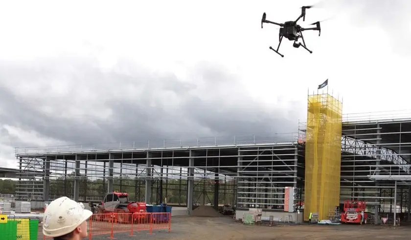 Survey drone mapping the MILVEHCOE site, with the steel frame of the main building behind