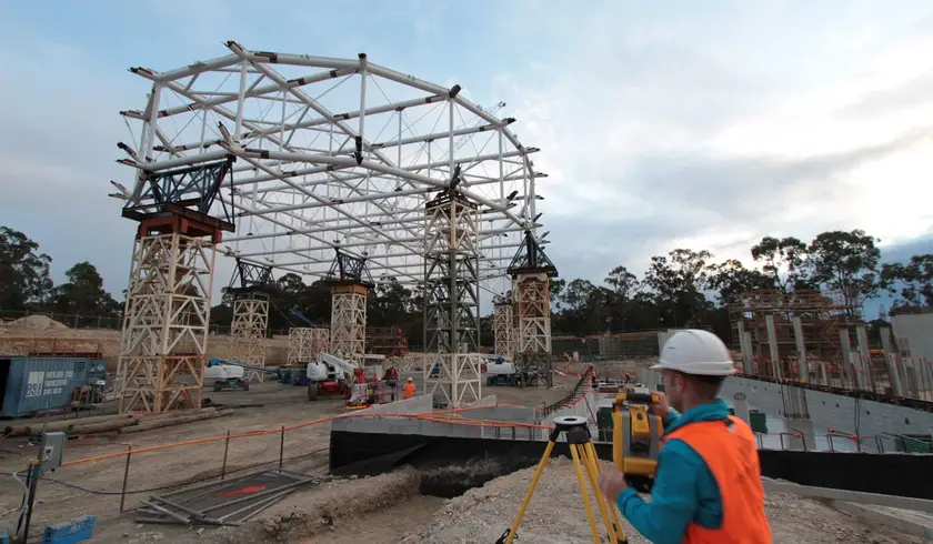 Surveyor checking the velodrome roof truss on its temporary support towers