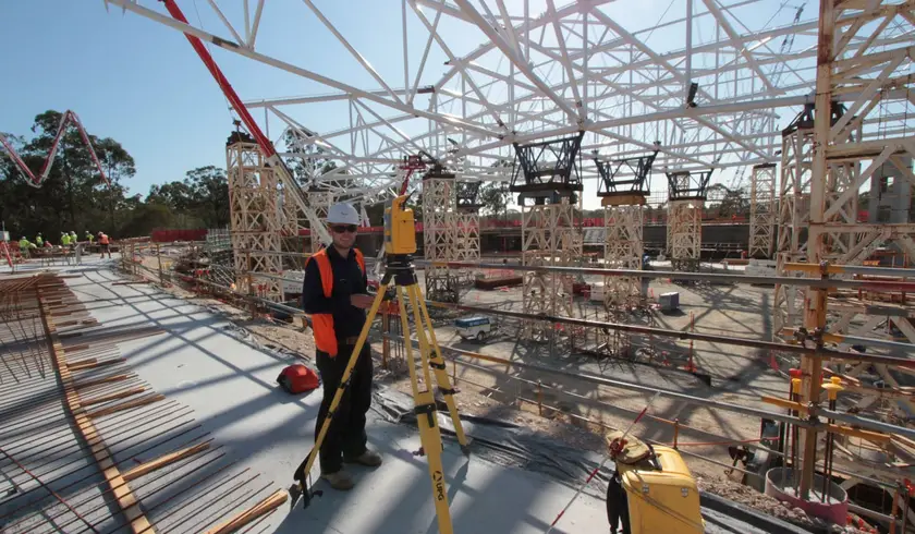 Surveyor with a total station beneath the velodrome steel roof truss