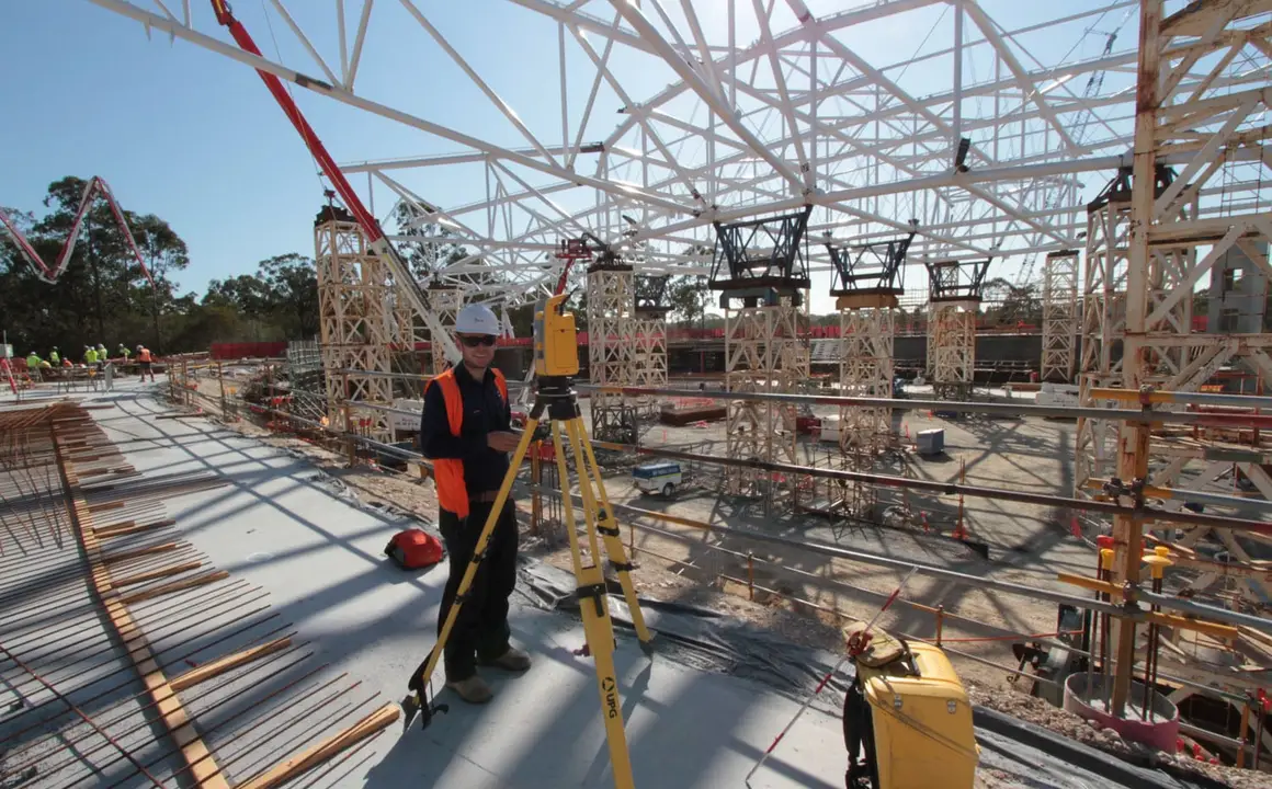 Surveyor with a total station beneath the velodrome steel roof truss